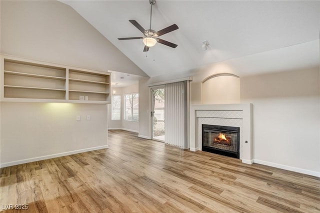 unfurnished living room featuring high vaulted ceiling, wood-type flooring, a tile fireplace, and ceiling fan