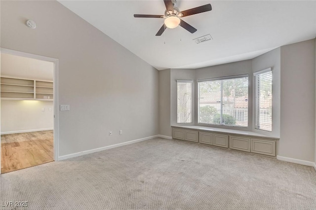 spare room with ceiling fan, light colored carpet, and lofted ceiling