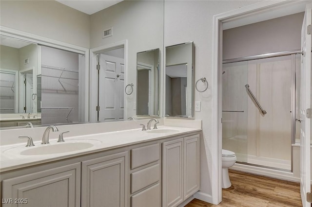 bathroom featuring hardwood / wood-style flooring, toilet, vanity, and a shower with shower door