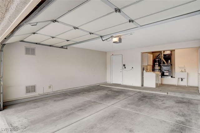 garage with separate washer and dryer, sink, a garage door opener, and gas water heater