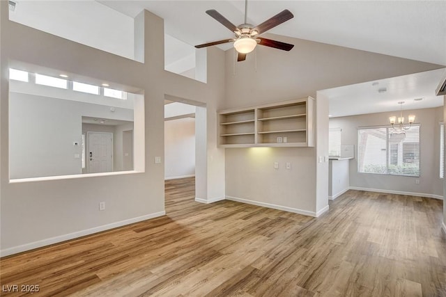 unfurnished living room with high vaulted ceiling, ceiling fan with notable chandelier, and light hardwood / wood-style floors