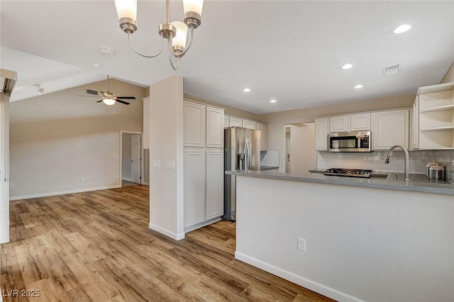 kitchen featuring tasteful backsplash, hanging light fixtures, kitchen peninsula, stainless steel appliances, and white cabinets