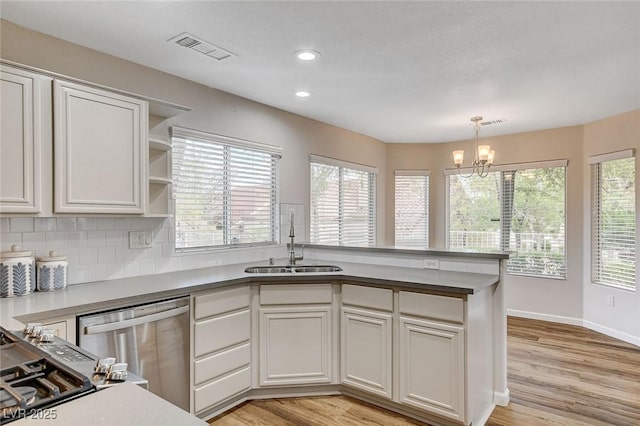 kitchen with sink, white cabinetry, hanging light fixtures, tasteful backsplash, and stainless steel dishwasher