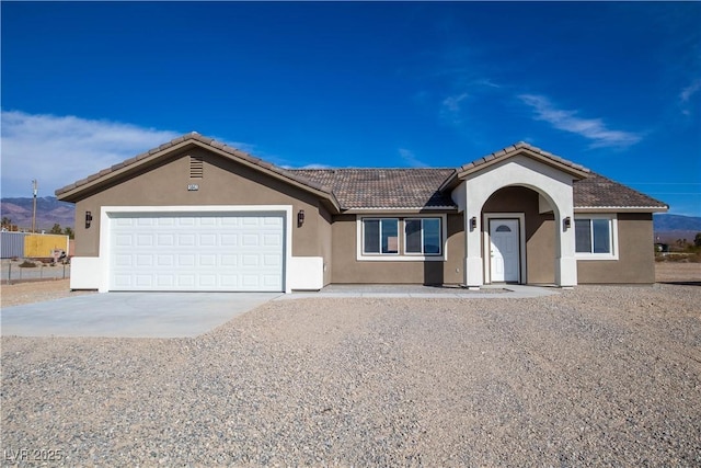 ranch-style home with a garage, concrete driveway, a tile roof, and stucco siding