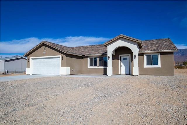 ranch-style home featuring concrete driveway, an attached garage, a tile roof, and stucco siding