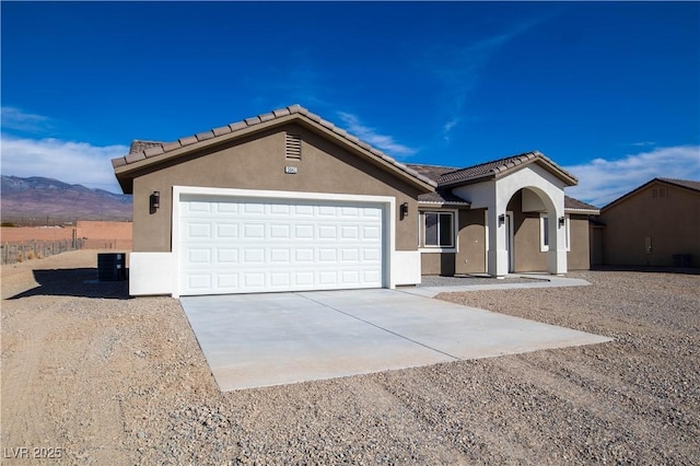 view of front of home with an attached garage, a mountain view, a tile roof, driveway, and stucco siding