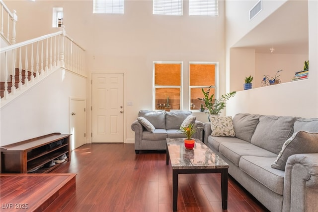 living room with dark wood-type flooring and a towering ceiling