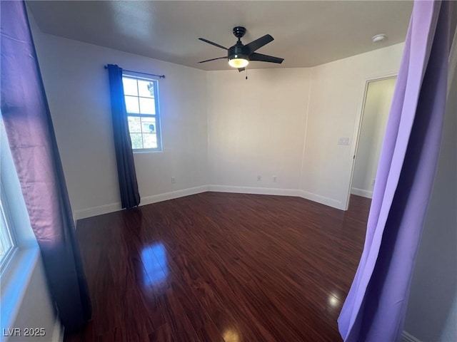 unfurnished room with a ceiling fan, baseboards, and dark wood finished floors