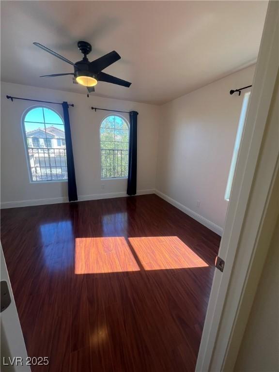 unfurnished room with baseboards, wood finished floors, and ceiling fan
