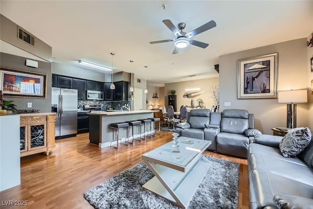 living room with light hardwood / wood-style flooring and ceiling fan