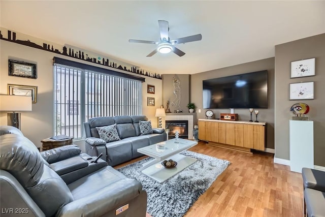 living room with light hardwood / wood-style floors, a tile fireplace, and ceiling fan