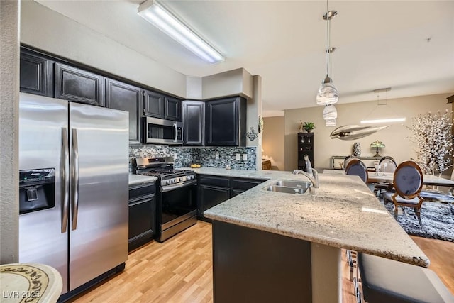 kitchen featuring decorative light fixtures, sink, decorative backsplash, kitchen peninsula, and stainless steel appliances