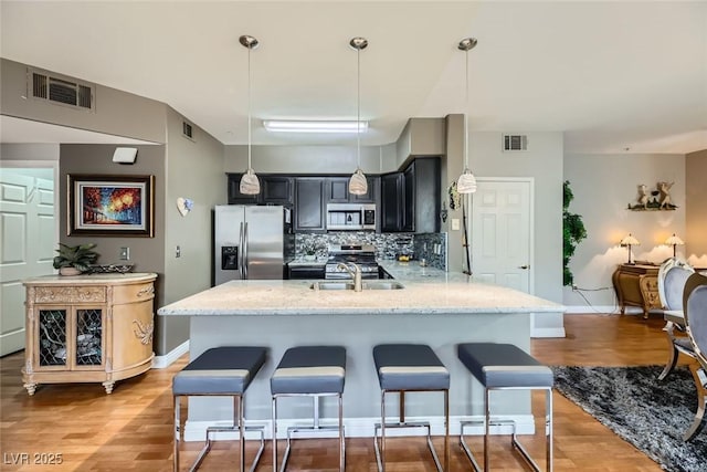 kitchen with appliances with stainless steel finishes, pendant lighting, tasteful backsplash, sink, and kitchen peninsula