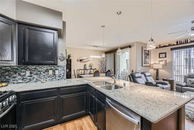 kitchen featuring pendant lighting, stainless steel appliances, light stone countertops, decorative backsplash, and kitchen peninsula