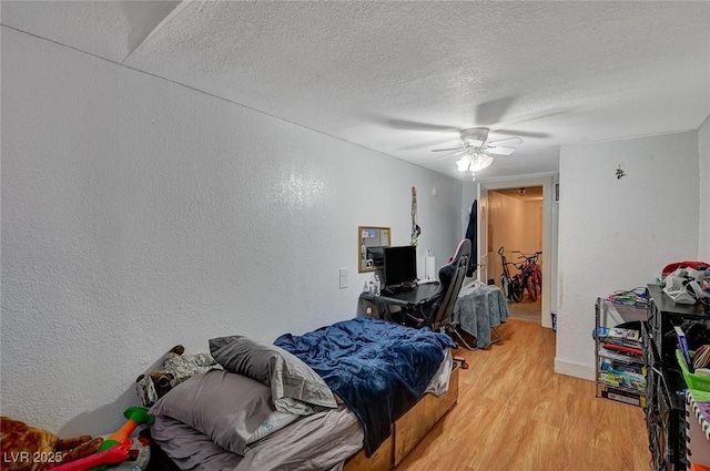 bedroom with ceiling fan, light hardwood / wood-style floors, and a textured ceiling