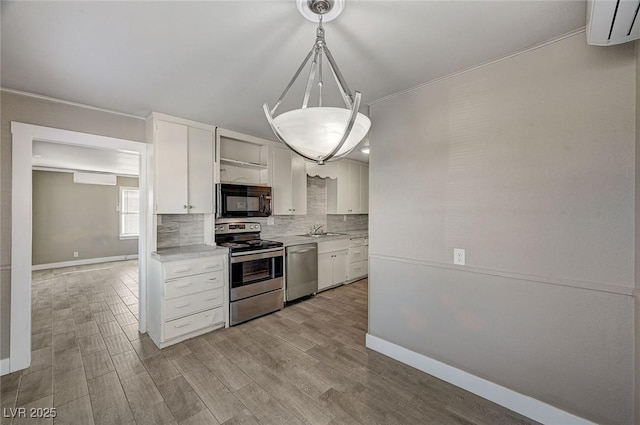 kitchen featuring appliances with stainless steel finishes, decorative light fixtures, tasteful backsplash, white cabinetry, and sink