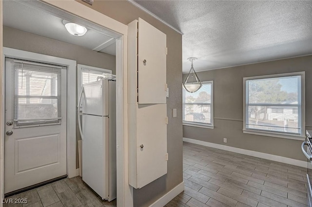 kitchen with white refrigerator, a textured ceiling, and pendant lighting