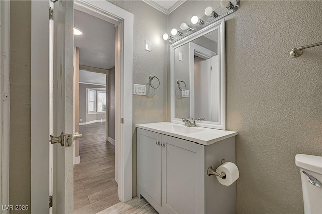 bathroom featuring ornamental molding, vanity, and toilet