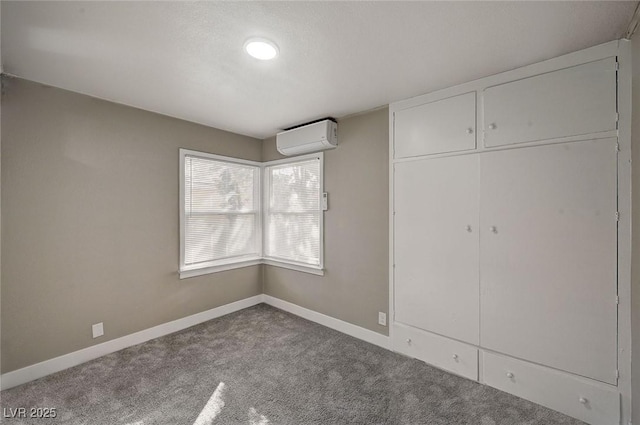 unfurnished bedroom with a closet, carpet floors, and a wall unit AC