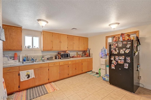 kitchen with black refrigerator, sink, and a textured ceiling