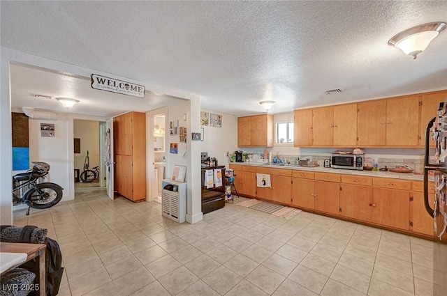632 D, Boulder City, NV 89005 - kitchen featuring stainless steel microwave, light countertops, a textured ceiling, and light tile patterned floors