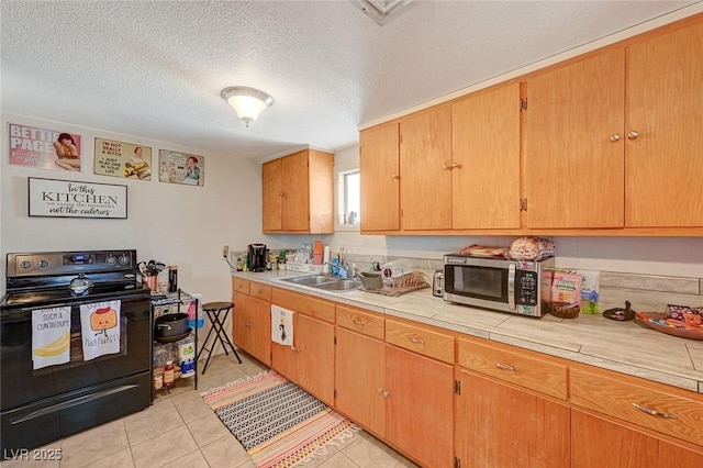 kitchen featuring light tile patterned floors, sink, tile counters, a textured ceiling, and black range with electric cooktop