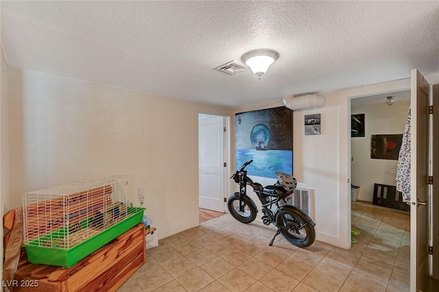 recreation room with light tile patterned floors and a textured ceiling