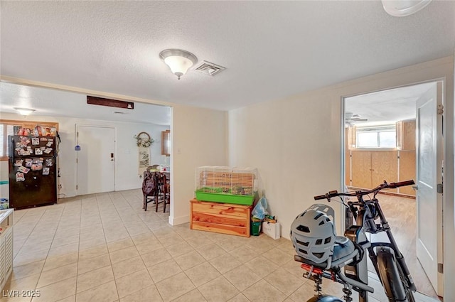 exercise room featuring light tile patterned flooring and a textured ceiling