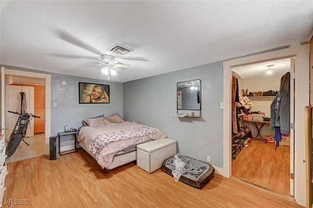 bedroom with ceiling fan, a spacious closet, light hardwood / wood-style floors, and a closet