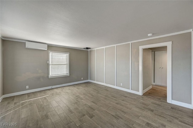 spare room with hardwood / wood-style flooring, ornamental molding, and an AC wall unit