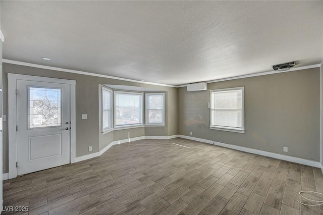 foyer featuring ornamental molding, wood-type flooring, a wall unit AC, and a textured ceiling