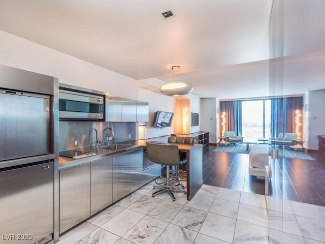 kitchen with stainless steel counters, sink, black electric stovetop, and backsplash