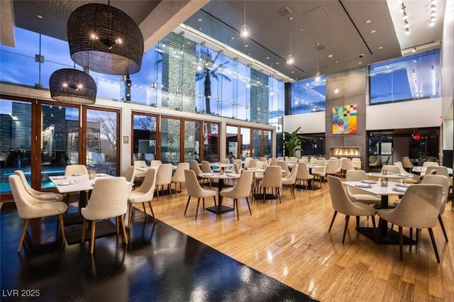 dining space with wood-type flooring and a towering ceiling