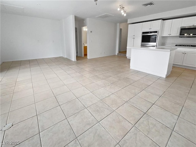 kitchen with light tile patterned floors, black gas cooktop, white cabinets, and a center island