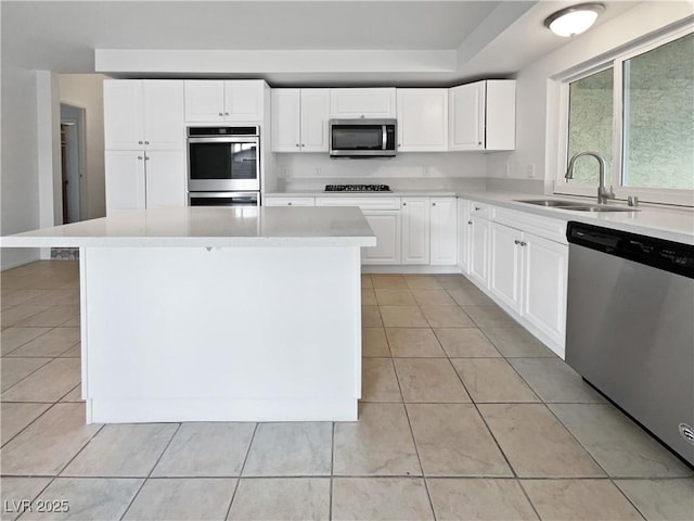 kitchen with light tile patterned flooring, sink, white cabinets, a center island, and stainless steel appliances