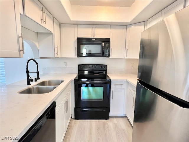 kitchen with sink, light hardwood / wood-style flooring, black appliances, and white cabinets