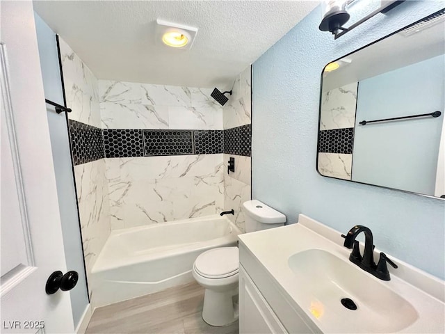 full bathroom with tiled shower / bath combo, vanity, hardwood / wood-style flooring, toilet, and a textured ceiling