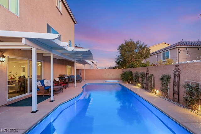 pool at dusk featuring a patio, a fenced backyard, a fenced in pool, and an outdoor living space