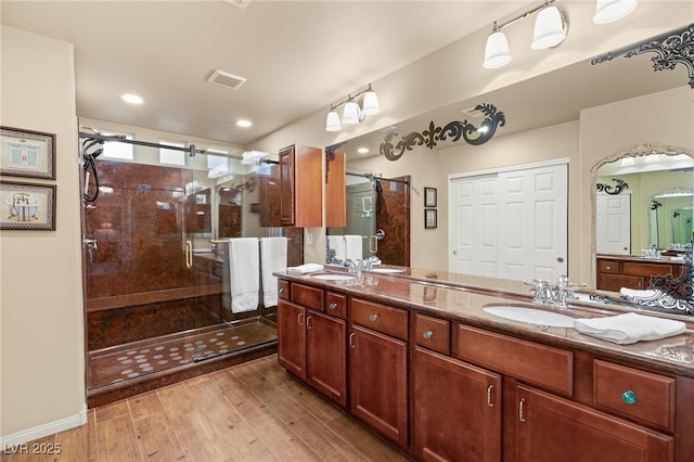 bathroom with visible vents, a stall shower, wood finished floors, and a sink