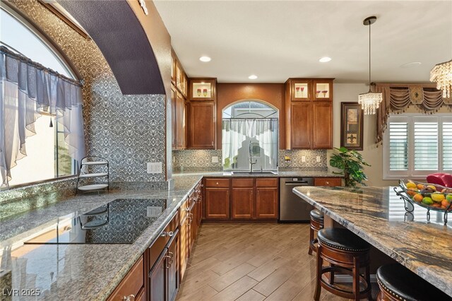 kitchen with stone countertops, pendant lighting, tasteful backsplash, sink, and stainless steel dishwasher