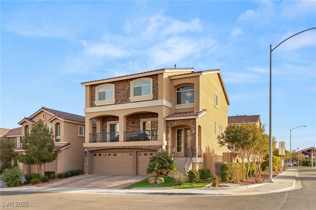 mediterranean / spanish-style home featuring a tiled roof, stucco siding, a garage, stone siding, and driveway