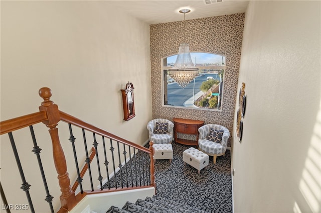 stairs featuring a notable chandelier, wallpapered walls, baseboards, and visible vents