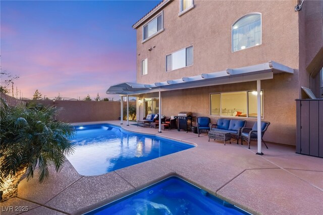 pool at dusk with a hot tub, a patio, and outdoor lounge area