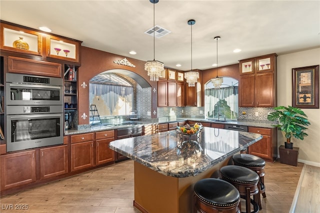 kitchen with visible vents, a sink, a center island, stainless steel appliances, and light wood finished floors