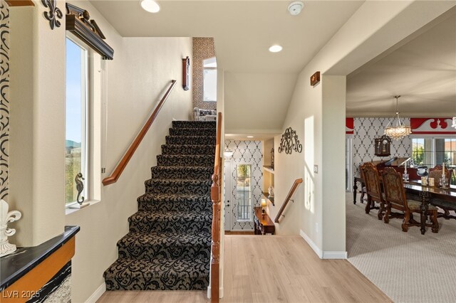 staircase featuring wood-type flooring and a chandelier