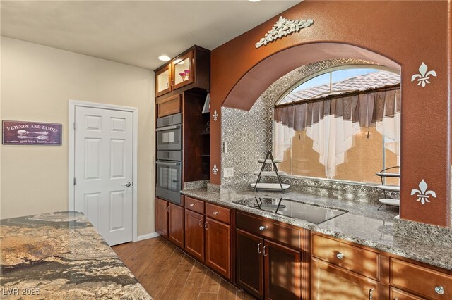 kitchen featuring stone countertops, hardwood / wood-style floors, and black appliances