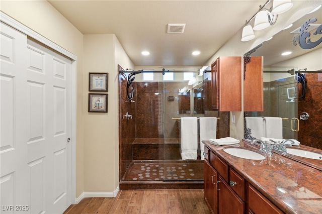 full bath with vanity, wood finished floors, visible vents, baseboards, and a stall shower