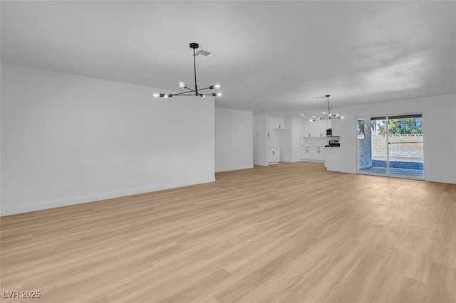 unfurnished living room with an inviting chandelier and light wood-type flooring