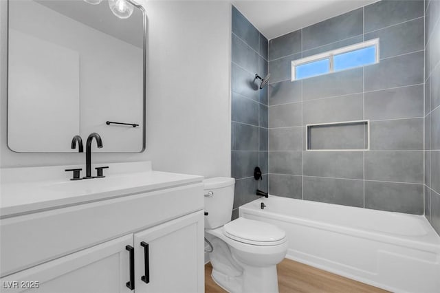 full bathroom with tiled shower / bath, hardwood / wood-style floors, vanity, and toilet