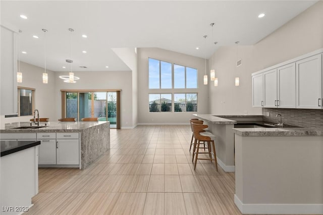 kitchen featuring sink, decorative light fixtures, dark stone countertops, decorative backsplash, and white cabinets